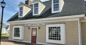 alt="Photo of routed HDU sign for dance studio mounted on tan siding building in Spotsylvania, Virginia"