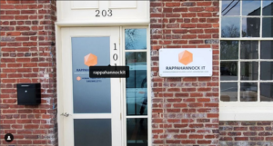 alt="Photo of various orange and white signs and graphics for front entrance of IT company located in downtown Fredericksburg, Virginia"