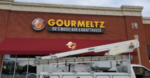 A front-facing shot of the Gourmeltz channel letter restaurant sign in Fredericksburg, VA, with a work truck beneath that has just finished installing the sign.