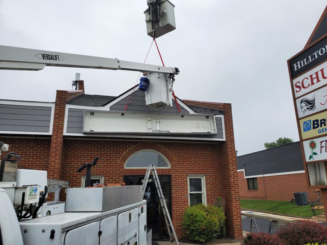 alt="Photo of sign cabinet being removed with bucket truck for existing shopping center in Spotsylvania, Virginia"