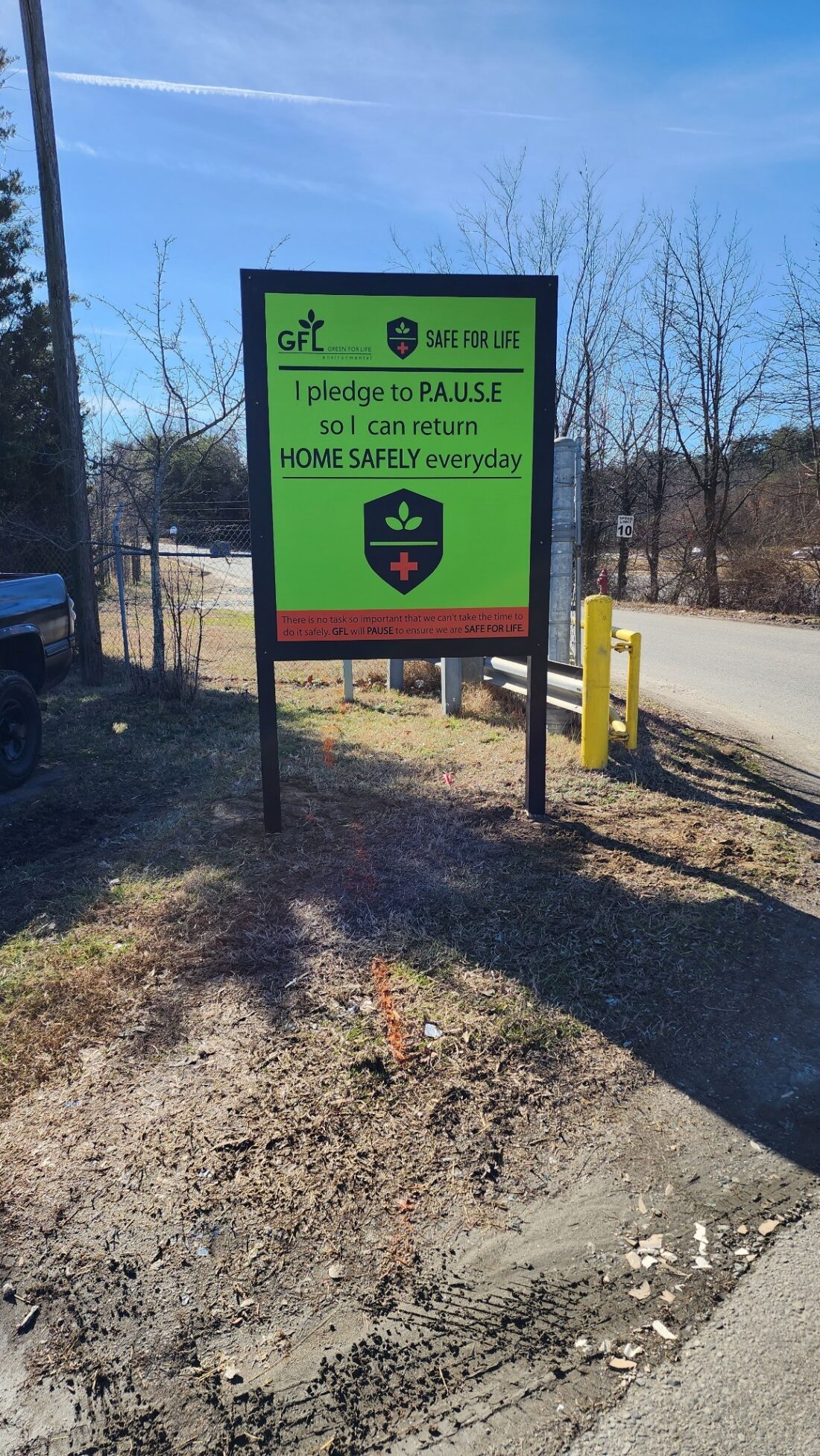 alt="Photo of vibrant lime green and orange post and panel sign for GFL Trash company located in Spotsylvania, Virginia"