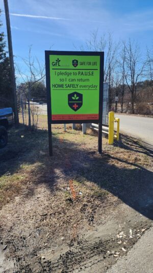 alt="Photo of vibrant lime green and orange post and panel sign for GFL Trash company located in Spotsylvania, Virginia"