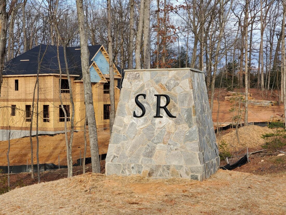 alt="Photo of black metal letters "SR" mounted to stone wall structure in Stafford, Virginia"