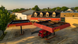 alt="Aerial Shot of red canopies and building with white and yellow channel letters for auto body shop, located in Fredericksburg, Virginia"