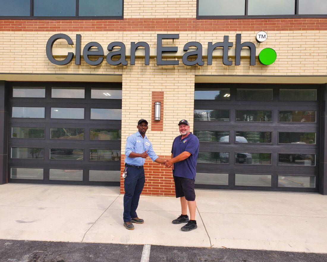 alt="Photo of happy customer and happy DSS employee shaking hands in front of black and lime green channel letter sign located in Spotsylvania, Virginia"