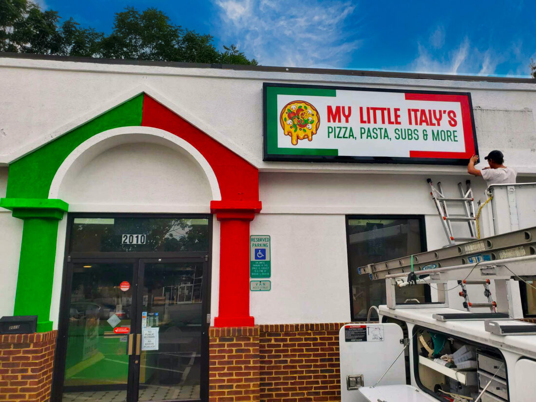 alt="Photo of installer finishing up Italian style pizza sign cabinet located in downtown Fredericksburg, Virginia"