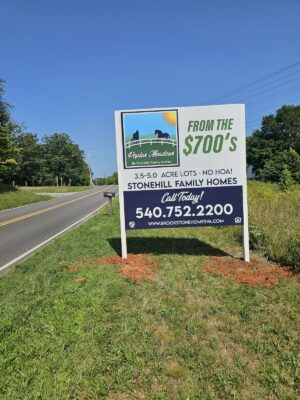 alt="Photo of large vibrant colorful home builder sign in large grassy area off of back road in Stafford, Virginia"