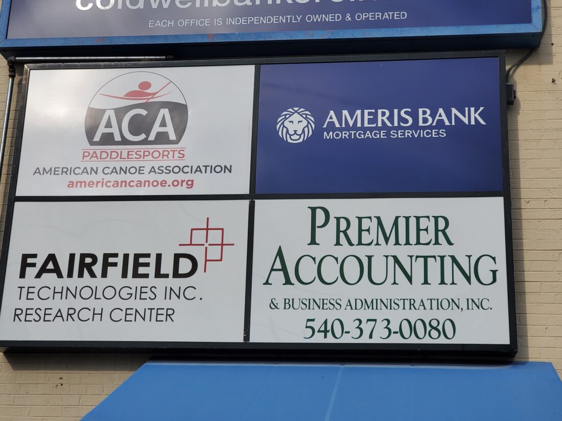 alt="Photo of sign cabinet with 4 different colorful tenant panels mounted on brick wall in Fredericksburg, Virginia"