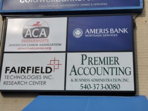 alt="Photo of sign cabinet with 4 different colorful tenant panels mounted on brick wall in Fredericksburg, Virginia"