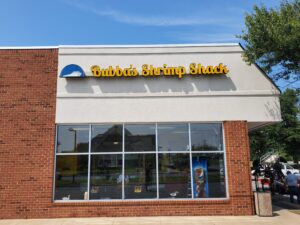 alt="Photo of yellow channel letter sign with blue logo with ship inside located on EIFS wall in Mechanicsville, Virginia"