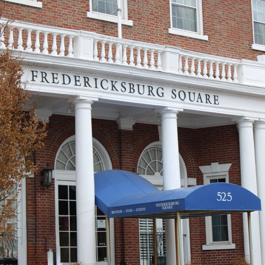 A blue business awning for Water’s End Brewery located in Fredericksburg, VA, with the words “Fredericksburg Square” written above the awning in gold lettering.