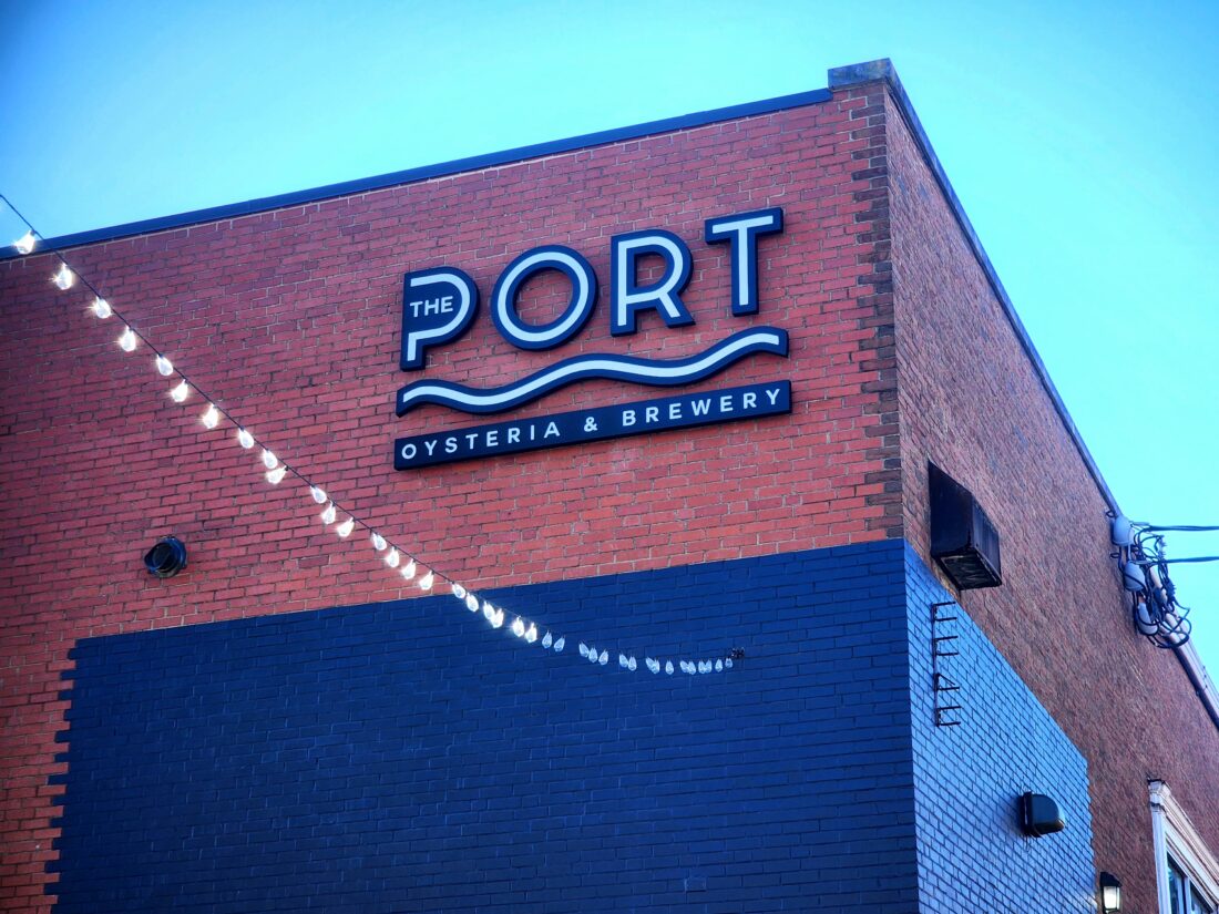 alt="Photo of black and white illuminated channel letter sign mounted on brick wall in downtown Fredericksburg, Virginia"