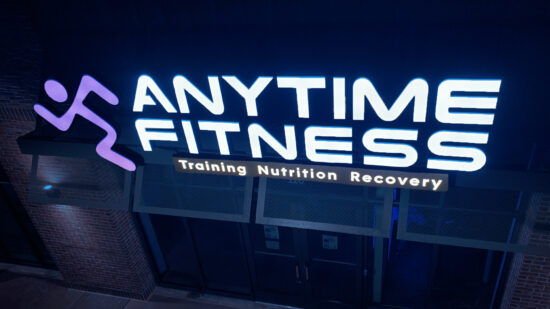 A brilliantly lit Anytime Fitness building sign illuminating the surroundings and standing out in the night.