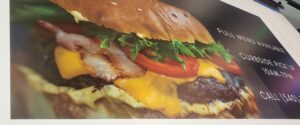 alt="Photo of banner sitting on flatbed printer displaying large, juicy, cheeseburger located in Fredericksburg, Virginia"