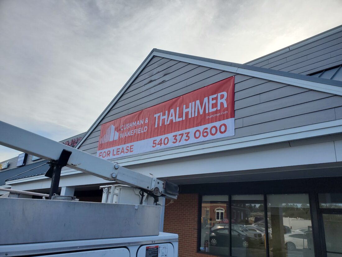 alt="Photo large red Thalhimer banner mounted to building siding gable located in Spotsylvania, Virginia"