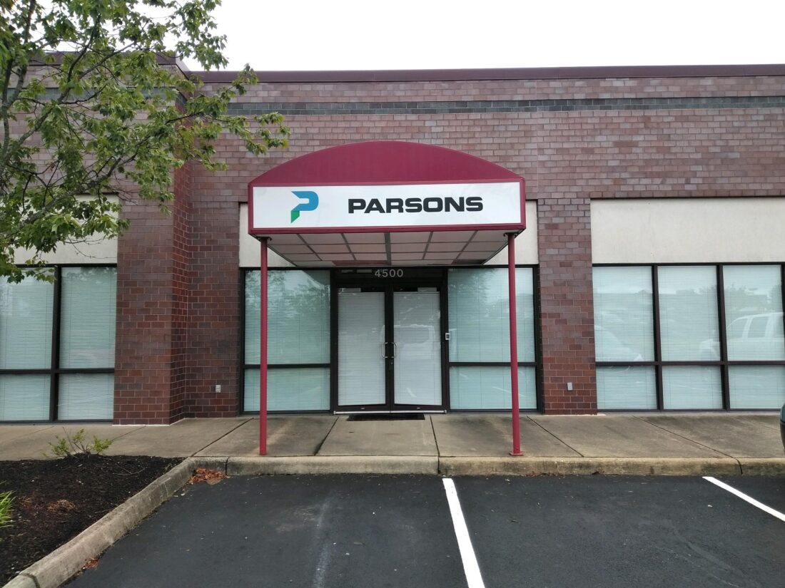 alt="Front facing photo of exterior awning on steel posts. Awning is maroon colored with logo on face stating PARSONS located in Spotsylvania, Virgina"