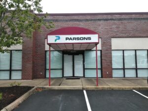 alt="Front facing photo of exterior awning on steel posts. Awning is maroon colored with logo on face stating PARSONS located in Spotsylvania, Virgina"