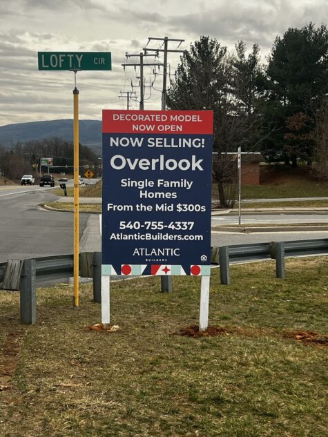 A vibrant post and panel sign by Atlantic Builders positioned at the intersection of Lofty Circle, announcing the decorated model now open for the 'Overlook' single-family homes, starting in the mid $300s, in Fredericksburg, VA.