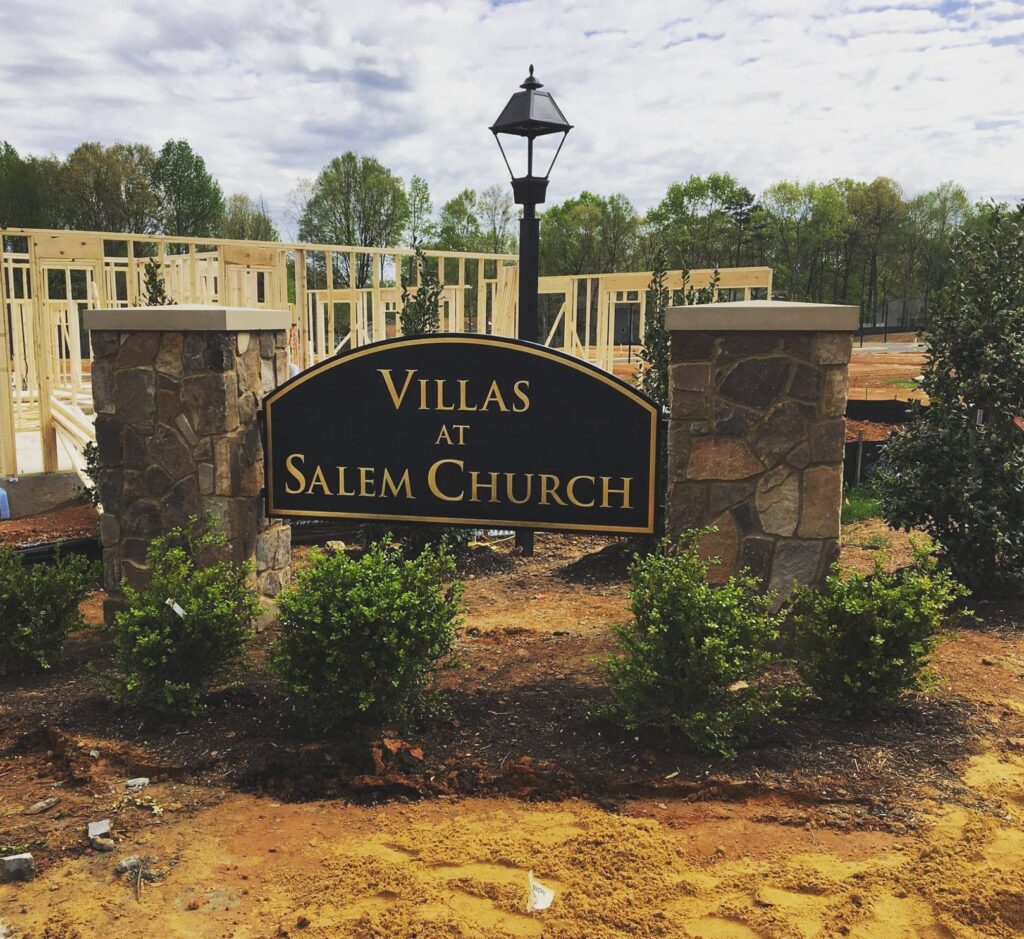 A beautifully crafted monument sign for the Villas at Salem Church by Distinct Sign Solutions, with gold lettering on a black background, set in a stone base, welcomes residents and visitors in Fredericksburg, VA.
