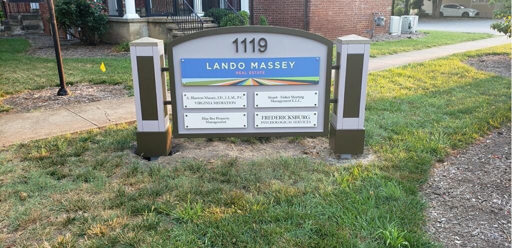 A professional monument sign by Distinct Sign Solutions displaying the name 'Lando Massey Real Estate' alongside other businesses, positioned on a well-manicured lawn in Fredericksburg, VA. A polished commercial real estate sign.