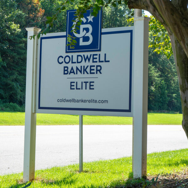 Blue and white Coldwell Banker Elite sign by Distinct Sign Solutions demonstrating clear visibility with bold fonts against a natural backdrop.