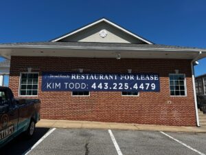 alt="Photo of brick wall with large blue Restaurant for Lease Graphic located in Fredericksburg, Virginia"