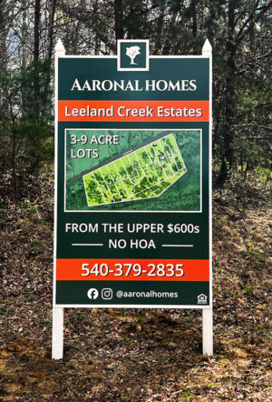 alt="Exterior Photo of large green, orange and white post and panel sign for Aaronal Home Leeland Creek Estates. The sign displays a site plan map and information about the sale located in Stafford, Virginia"