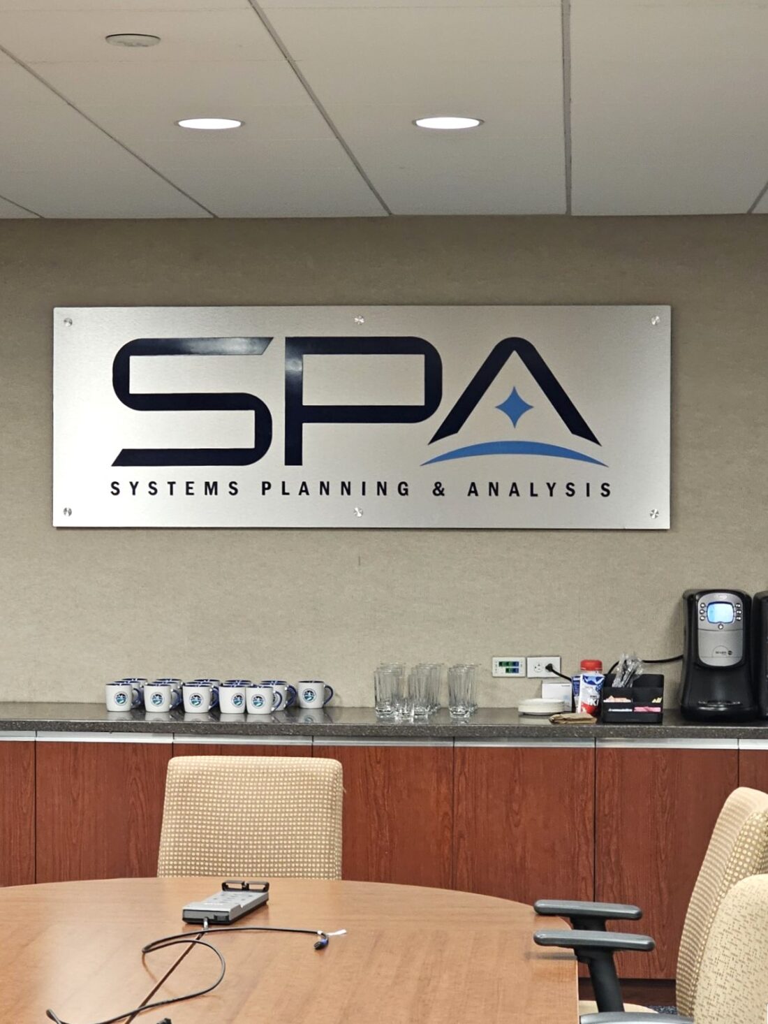 Photo of custom acrylic logo sign mounted to brushed aluminum backer frame for conference room wall in Washington DC. Sign was manufactured & installed by Distinct Sign Solutions in Fredericksburg, VA.