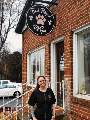 Photo of happy customer after Distinct Sign Solutions of Fredericksburg, VA installed her new blade sign for pet grooming shop in Dumfries, VA