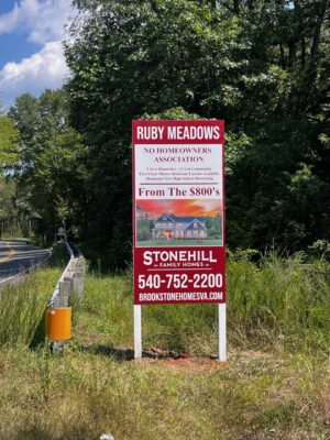 Photo of bright red sign installed in field located in Stafford, VA for Stonehill Family Homes. Sign was manufactured & installed by Distinct Sign Solutions in Fredericksburg, VA