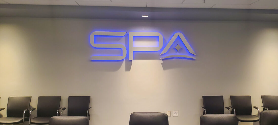 Photo of boardroom with brushed aluminum halo letter sign projecting blue light in Alexandria, VA.