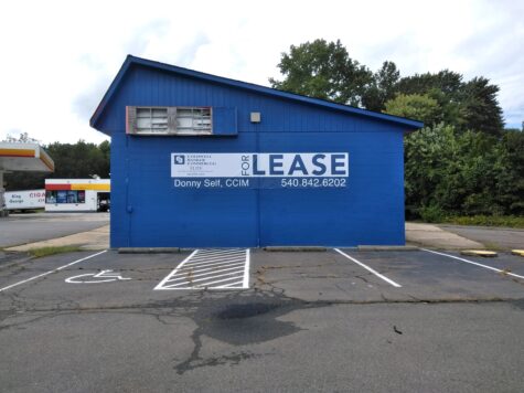 Photo of real estate banner installed on blue building in King George, VA. Banner was manufactured & installed by Distinct Sign Solutions in Fredericksburg, VA