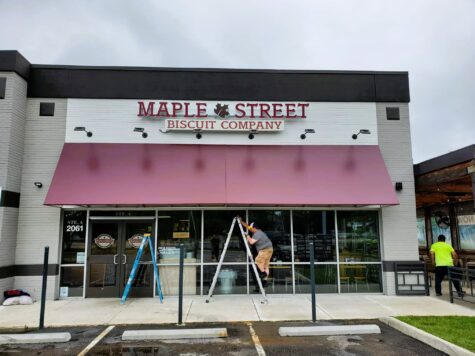 Photo of installer doing final touches on awning for Maple Street Biscuit company in Richmond, VA. Awning was recovered by Distinct Sign Solutions in Fredericksburg, VA