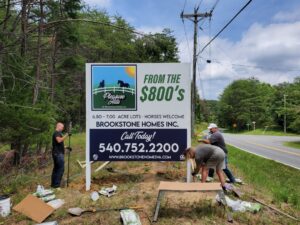 Photo of 3 installers doing finishing touches on large home builder sign in Stafford, VA. Sign was manufactured & installed by Distinct Sign Solutions in Fredericksburg, VA