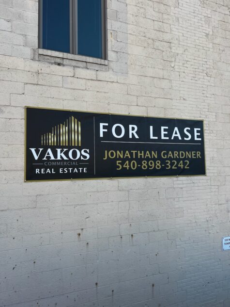 Photo of large commercial real estate banner mounted to wall for Vakos Real Estate in Fredericksburg, VA. Banner was manufactured & installed by Distinct Sign Solutions in Fredericksburg, VA