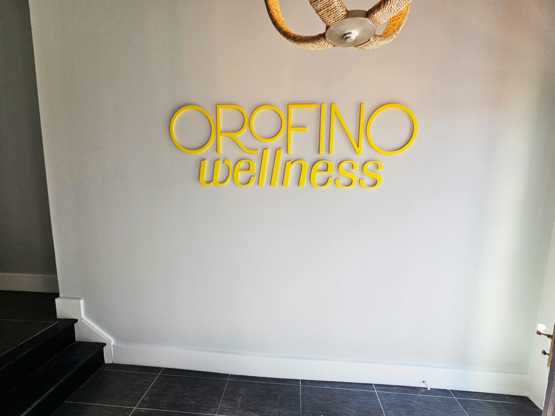 Photo of Orofino Wellness yellow acrylic wall sign for entrance at Pilates studio in Fredericksburg, VA. Sign was manufactured & installed by Distinct Sign Solutions in Fredericksburg, VA