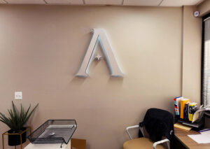 Photo of illuminated brushed metal illuminated sign at entrance reception area for Atlantic Builders in Fredericksburg, VA. Sign was manufactured & installed by Distinct Sign Solutions in Fredericksburg, VA