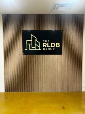 Photo of black and gold acrylic wall sign mounted to wooden slat wall in Stafford, VA contractor's office. Sign was manufactured & installed by Distinct Sign Solutions in Fredericksburg, VA