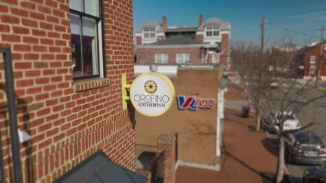 Aerial photo of yellow blade sign adorning Orofino Wellness lemon logo in Downtown Fredericksburg, VA. Sign was manufactured & installed by Distinct Sign Solutions in Fredericksburg, VA