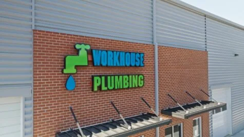 Photo of neon green & neon blue channel letter sign reading Workhouse Plumbing mounted on brick walled building in Stafford, VA. Sign was manufactured & installed by Distinct Sign Solutions in Fredericksburg, VA