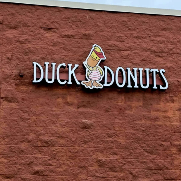Duck Donuts building sign with custom channel letters and mascot on red brick exterior.