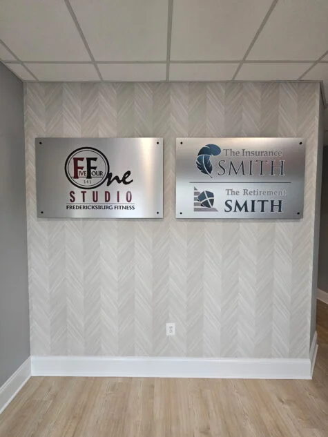 Photo of two brushed aluminum wall signs set on entrance wall in Fredericksburg, VA. Signs were manufactured & installed by Distinct Sign Solutions in Fredericksburg, VA