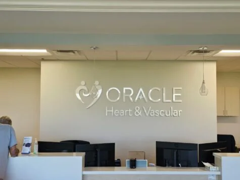 Photo of white acrylic wall sign set on standard cream drywall in receptionist area in Fredericksburg, VA. Sign was manufactured & installed by Distinct Sign Solutions in Fredericksburg, VA