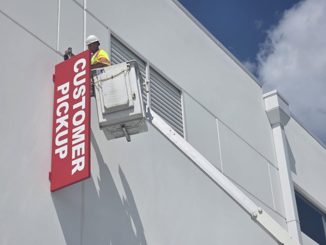 Photo of installer in bucket truck doing finishing touches on red blade sign for O'Reilly Auto Parts saying "CUSTOMER PICKUP" in Stafford, VA. Sign was installed by Distinct Sign Solutions in Fredericksburg, VA