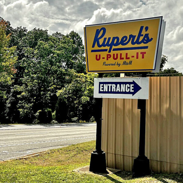 Freestanding entrance sign for Rupert’s U-Pull-It with directional arrow pointing toward gate