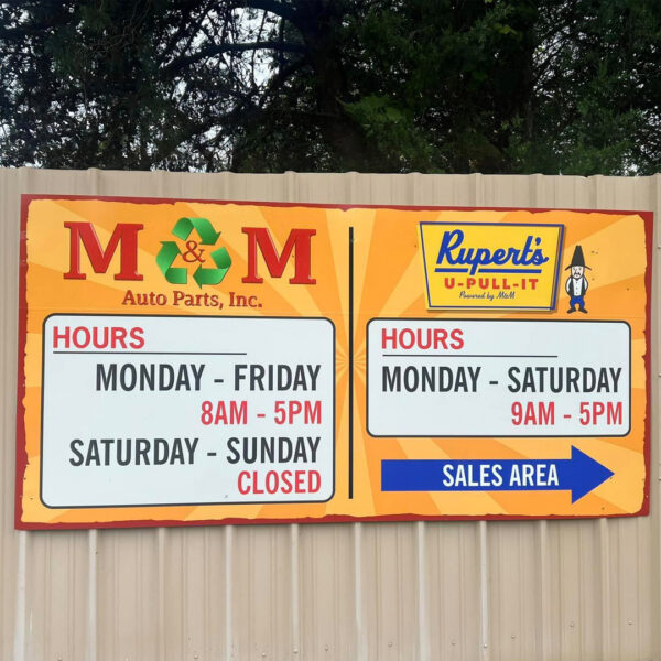 Wall-mounted business hours sign for M&M Auto Parts and Rupert’s U-Pull-It with directional arrow to sales area
