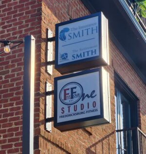 Photo of two stacked blade signs mounted to brick wall for The Insurance Smith and 541 Studio, located in downtown Fredericksburg, VA. Signs were manufactured & installed by Distinct Sign Solutions in Fredericksburg, VA