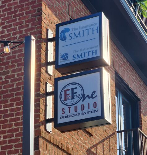 Photo of two stacked blade signs mounted to brick wall for The Insurance Smith and 541 Studio, located in downtown Fredericksburg, VA. Signs were manufactured & installed by Distinct Sign Solutions in Fredericksburg, VA