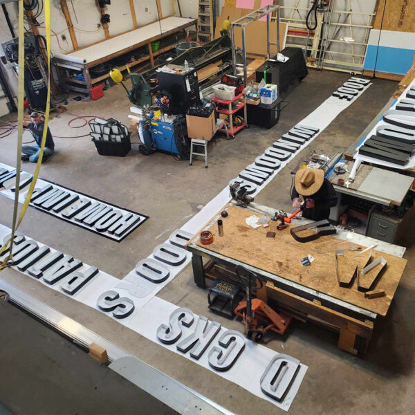 Technicians laying out and wiring halo-lit letters on the shop floor.