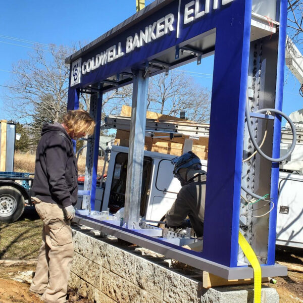 Technicians wiring the aluminum frame for a UL-Listed LED message center during install at Coldwell Banker Elite.